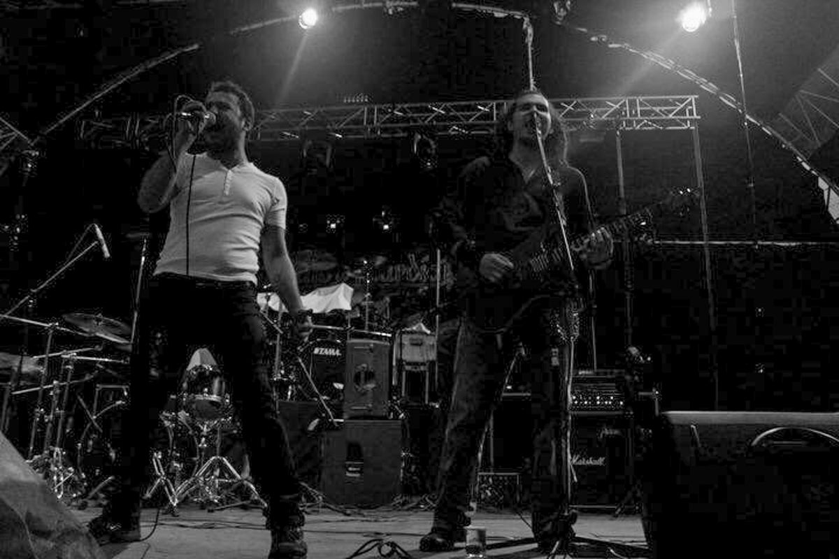 Two musicians performing on stage with instruments and equipment.