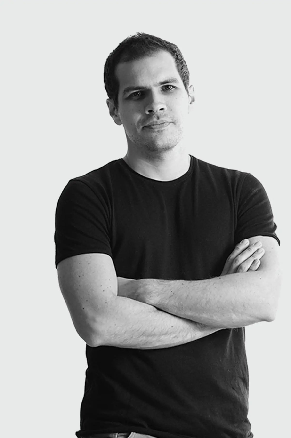 Black and white portrait of a person with arms crossed on a light background