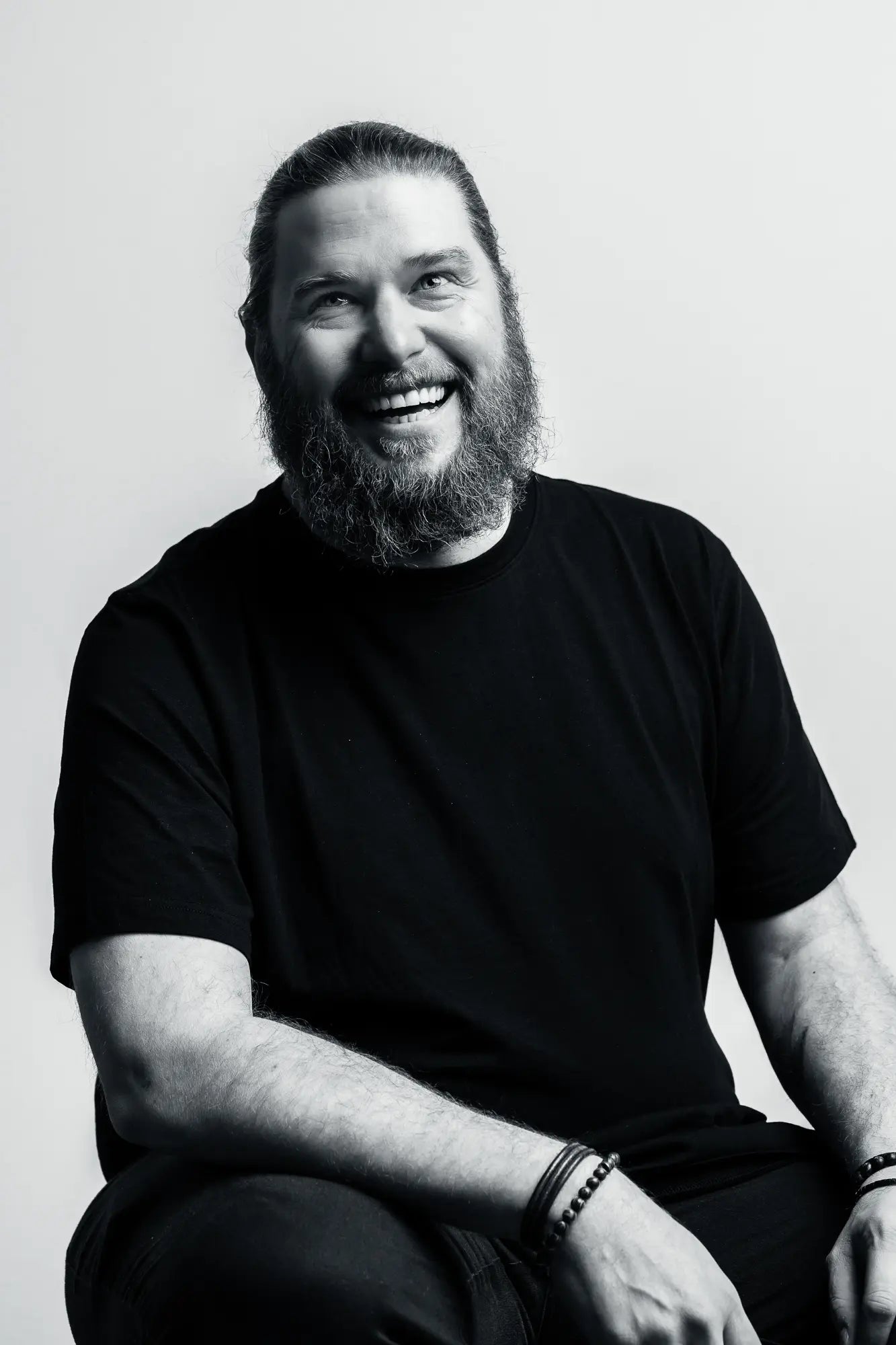 Black and white portrait of a man with a beard smiling against a plain background
